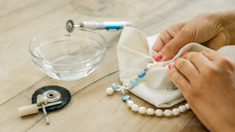 Mani che lucidano una collana di perle con un panno